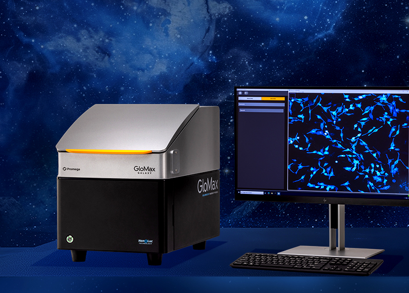 Das GloMax® Galaxy Bioluminescence Imager-System von Promega: links das Mikroskop mit dem Logo und einem sanften orangefarbenen Leuchten, rechts ein Computerbildschirm, der eine biolumineszente Zellbildgebung in leuchtendem Blau vor einem dunklen, galaxienartigen Hintergrund zeigt